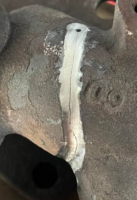 Cast iron crack ground into a V with a stop-drill hole at the end of the crack
